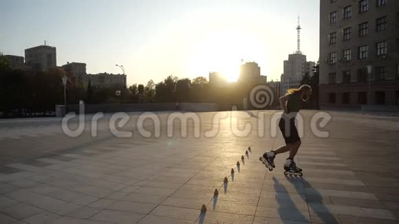 傍晚时分年轻的长发男子溜冰者正在一个城市公园里的球果间跳舞自由式回转视频的预览图