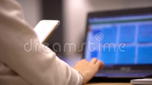 女人用手提电脑拿着智能手机女商人使用便携式电脑和视频的预览图