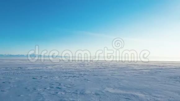 在晴朗的冬季用一个钻孔机从上面捕捉到的冰雪覆盖的贝加尔湖表面的空中透视视频的预览图
