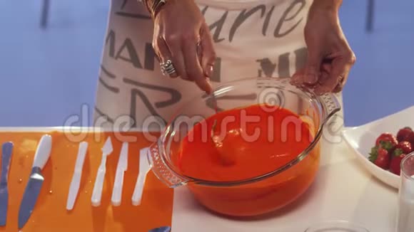 女人她的手在桌上的大玻璃锅里用勺子搅拌橘子粥视频的预览图