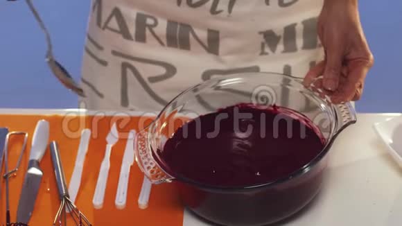 女人她的手用勺子在桌子上的大玻璃锅里搅拌紫罗兰的物质视频的预览图