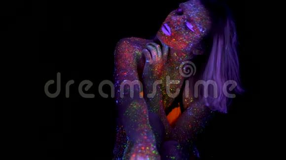 美丽的粉红头发女人在霓虹灯紫外光中抚摸自己的身体有荧光创意的迷幻化妆的模特女孩视频的预览图