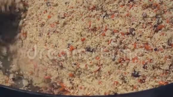 在大锅里煮皮拉夫用厨房勺子混合皮拉夫亚洲传统烹饪菜肴皮拉夫视频的预览图