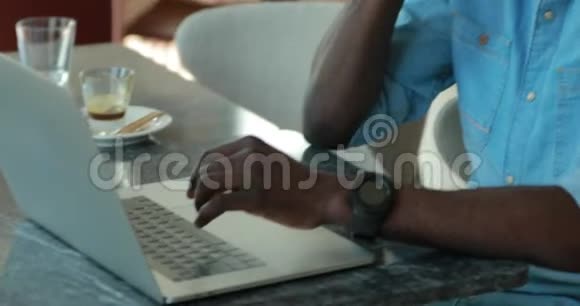 非裔美国商人在咖啡馆里用手提电脑边打电话视频的预览图