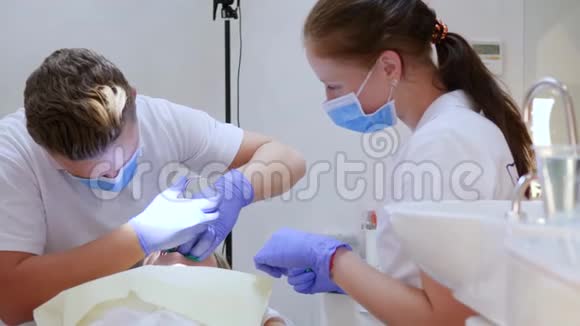 戴手套和口罩的医务人员在门诊治疗躺卧者的牙齿视频的预览图