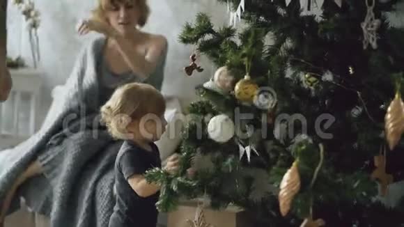 幸福的家庭和可爱的小女儿准备打开礼物盒附近的圣诞树在家视频的预览图