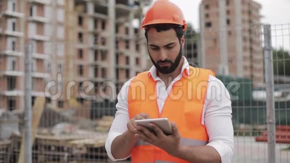 建筑工地上建筑工人的肖像用平板电脑看着摄像机职业建筑工人视频的预览图
