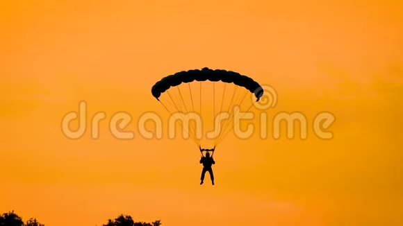 夏季日落时分跳伞运动员在金色天空中跳伞的剪影视频的预览图