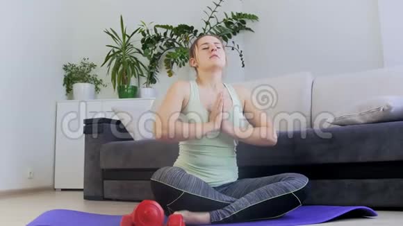4K镜头美女坐在家里的瑜伽垫上沉思视频的预览图