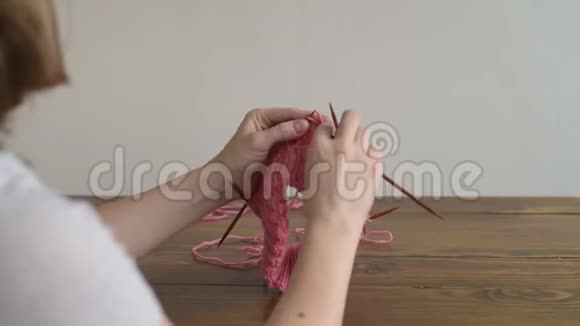 在木桌上编织一顶粉红色的帽子视频的预览图