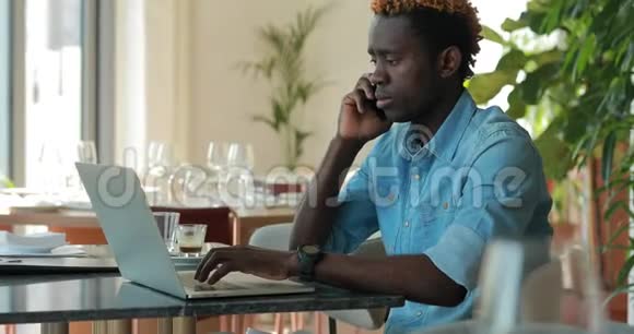 快乐的非裔美国商人在咖啡馆里用手提电脑聊天视频的预览图