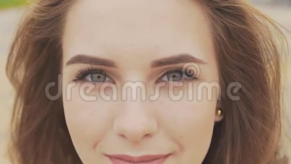 一个漂亮的年轻女孩的脸深蓝色的眼睛特写脸上整齐的日妆性感的表情视频的预览图
