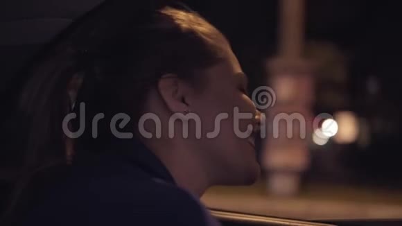快乐美丽的女孩晚上坐在出租车上坐在后座上从窗户望着夜城视频的预览图