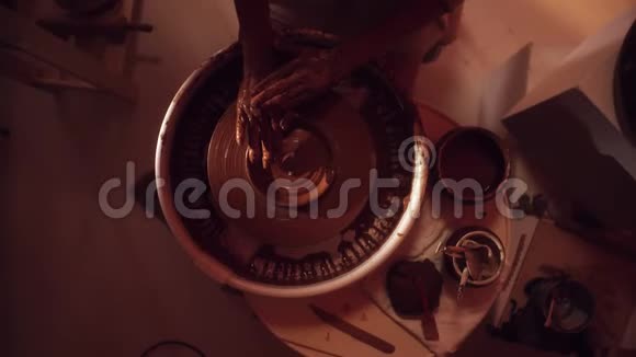 在暗光工作室中旋转陶工轮上成型陶土的过程视频的预览图