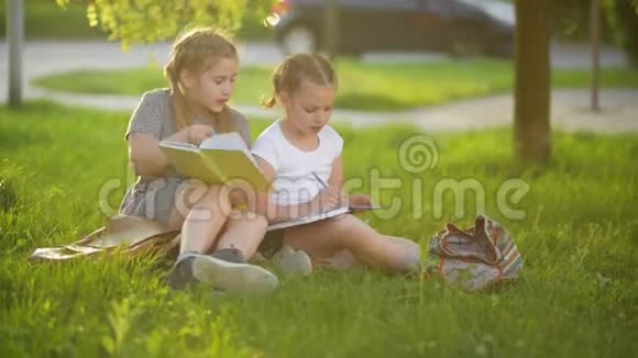 孩子们在夏天的花园里看书学前朋友玩耍学习做家庭作业的女孩视频的预览图