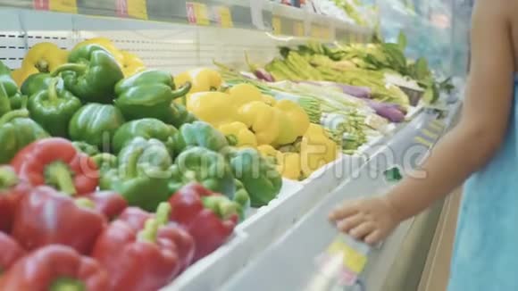 小女孩走过货架在杂货店买蔬菜后景视频的预览图