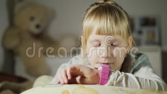 一个女孩正在玩她手臂上的智能时钟躺在卧室的床上视频的预览图