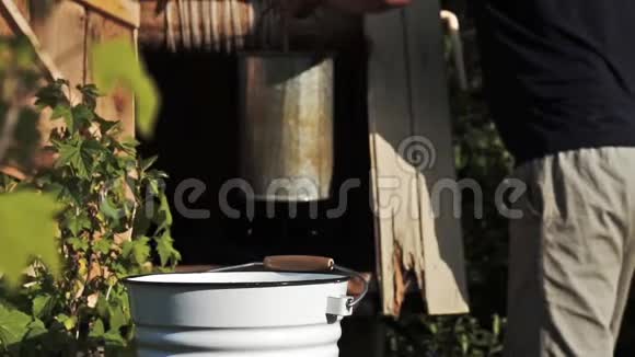 一个人在夏天把水从井里倒进水桶里的慢镜头视频的预览图