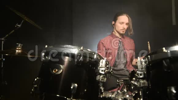 一位长头发的鼓手坐在鼓旁手里拿着鼓棒随着音乐的节拍在介绍中摇摆视频的预览图