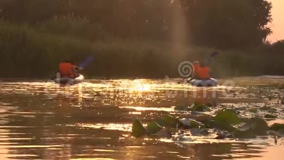 两条皮划艇与人们划桨进入日落视频的预览图
