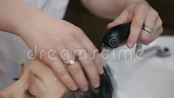 特写镜头发型师在美容院或理发店里给年轻人洗头发理发师男士洗头视频的预览图