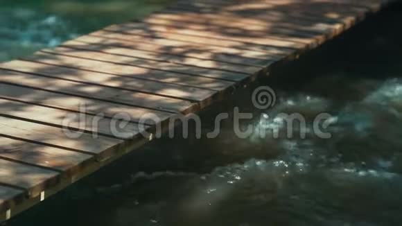 一座小木桥穿过一条有石头的山河慢速高清视频的预览图