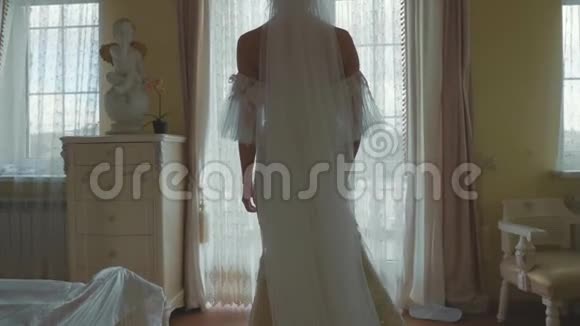 年轻新娘穿着婚纱从客厅到阳台慢动作视频的预览图