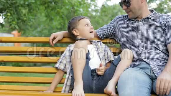 父亲和儿子坐在长凳上视频的预览图