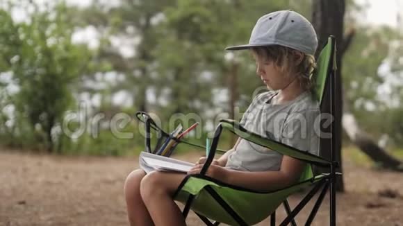 孩子在木头背景上的笔记本上做素描视频的预览图