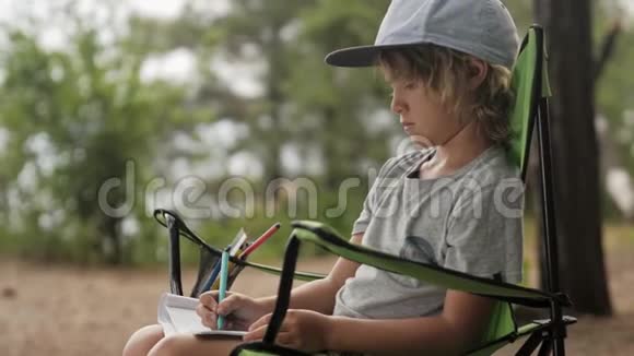 孩子在木头背景上的笔记本上做素描视频的预览图
