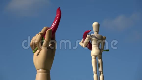 在天空背景上旋转木制人体模型手拿红辣椒视频的预览图