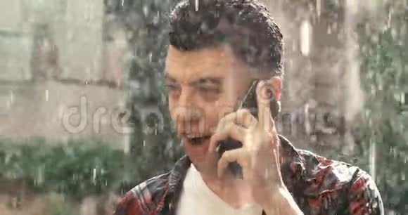 雨中幸福微笑的男人在手机上有感情地交谈的肖像4K录像视频的预览图
