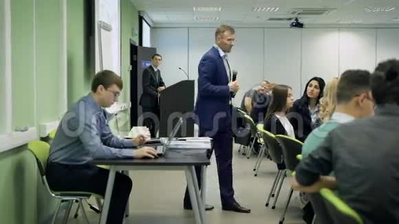 讲师在一个关于经济学的讲座上对学生讲话男性手势并显示投影仪的图像视频的预览图