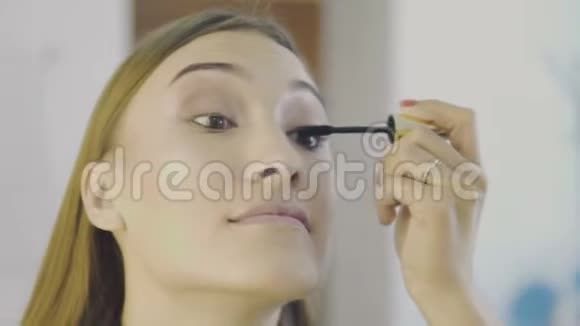 化妆师的手睫毛膏刷和年轻女人的脸Visagist是用黑色在睫毛上作画视频的预览图