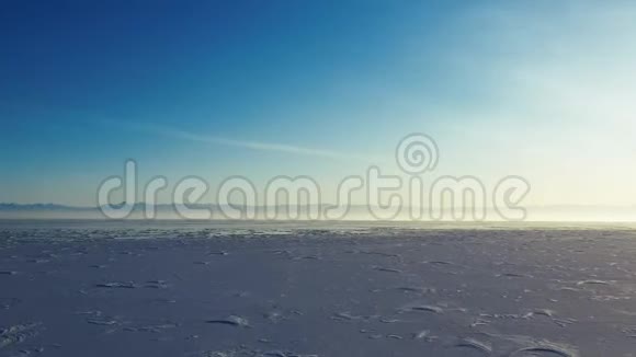 在晴朗的冬季用一个钻孔机从上面捕捉到的冰雪覆盖的贝加尔湖表面的空中透视视频的预览图