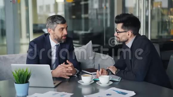 男性同事在现代咖啡馆午休时讨论生意视频的预览图