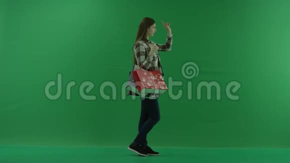 女孩们站在她的右边拿着包裹从绿色背景上的屏幕上选择一些东西视频的预览图