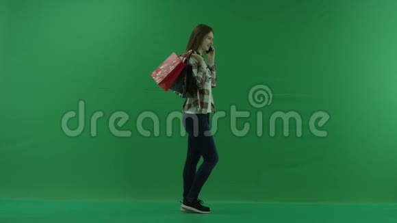 女孩站在她的右边肩上扛着袋子在绿色屏幕上通过电话交谈视频的预览图