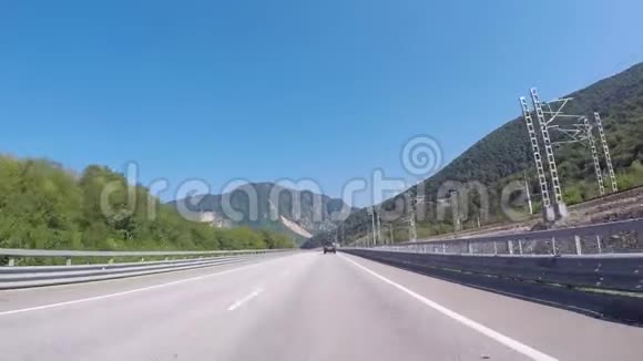 汽车行驶在铁路附近的高速公路上与蓝天和白种人的山脉相对场景索契克拉斯诺达尔地区视频的预览图