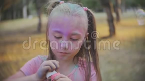 可爱的小女孩在阳光明媚的一天在花园里吹肥皂泡慢动作视频的预览图