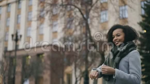 漂亮的非裔美国学生女孩检查智能手表并在大学附近走开视频的预览图