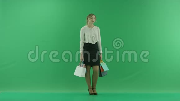 带着购物袋的漂亮购物女人女购物者手里拿着购物袋一半是绿色背景的视频的预览图
