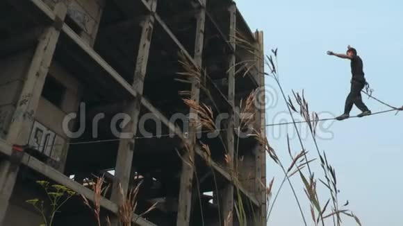 在一个废弃的建筑工地上一个人在高处用绳子行走视频的预览图