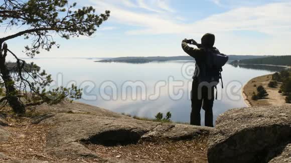 一位年轻的男性游客在下午用智能手机拍照度假冒险的剪影视频的预览图