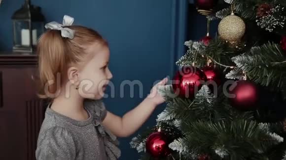 非常漂亮的小女孩站在新年树附近触摸玩具视频的预览图