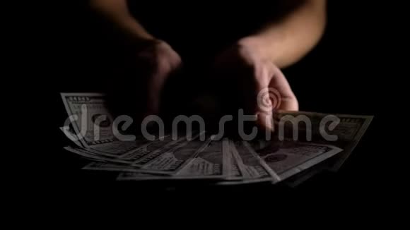 一个人在黑暗中挥舞着一把美元的扇子他从风扇里收集美元成堆4K慢动作视频的预览图