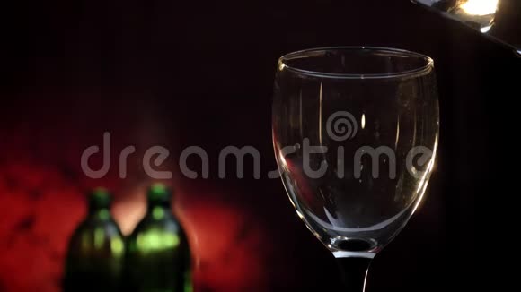 将白葡萄酒倒入玻璃杯中两瓶和红色背景酒精饮料灌装杯视频的预览图
