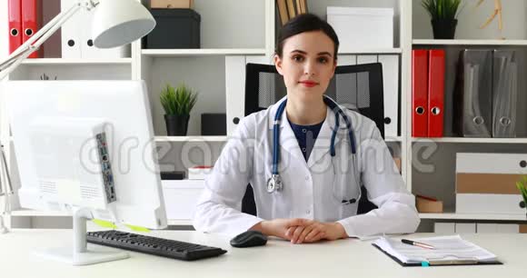 穿白色实验室外套的医生坐在工作场所看文件视频的预览图