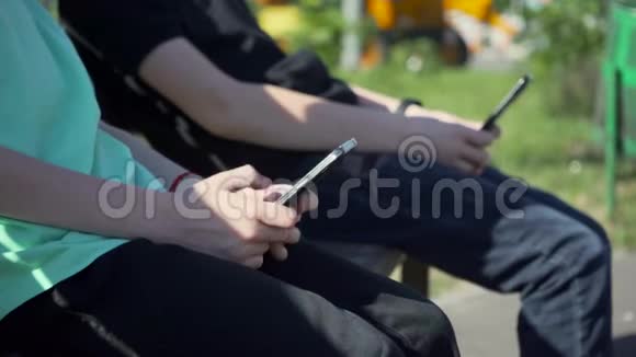 镜头与跟随焦点男孩与黑色智能手机坐在板凳上玩游戏录制6k视频视频的预览图