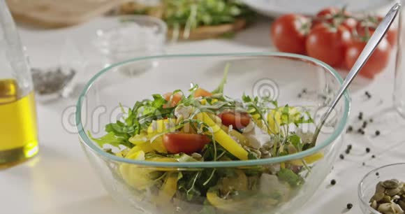 橄榄油是用勺子倒入一个玻璃碗里面有机蔬菜奶酪和南瓜籽沙拉慢动作视频的预览图